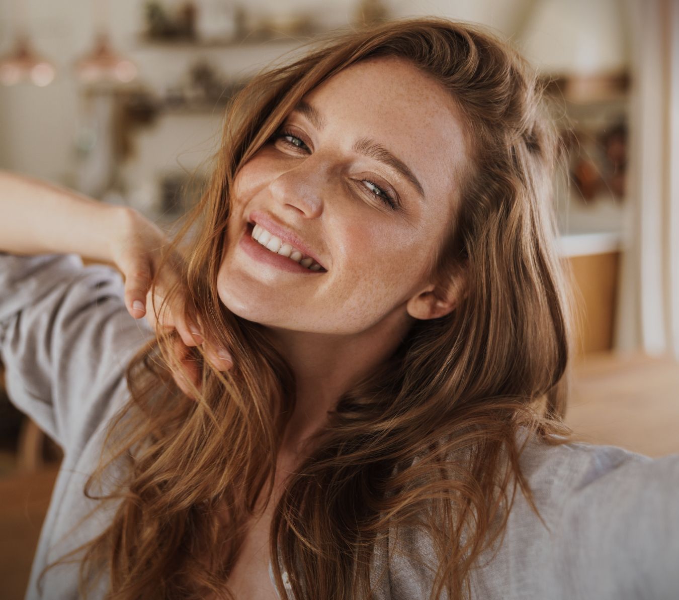 Smiling woman with long, wavy hair indoors.